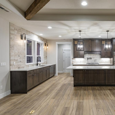 Modern kitchen with dark wood cabinets, marble countertops, and stone accent wall.